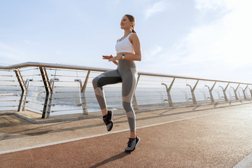 Happy female doing jog in place on bridge