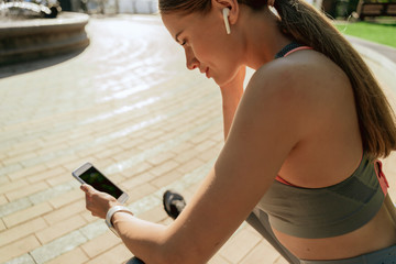 Sportive lady in headphones with mobile phone