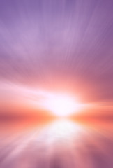 Abstract Bright sun at sunset on the background of clouds and blue sky over the sea.