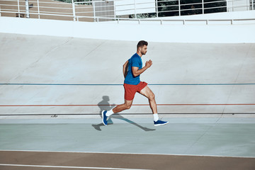 Adult sportsman running on stadium in city