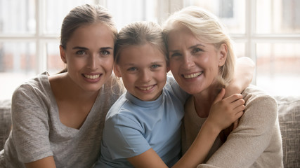 Three generations of women sitting on couch looking at camera