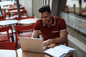 Obraz premium Young man is using modern laptop in cafe