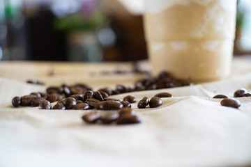 Defocused Background of Coffee beans on table with coffee plastic cup.