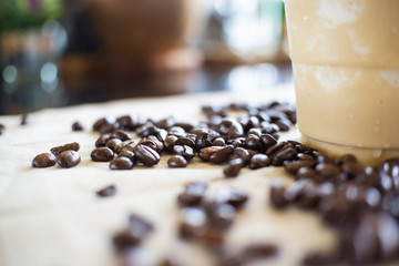 Defocused Background of Coffee beans on table with coffee plastic cup.
