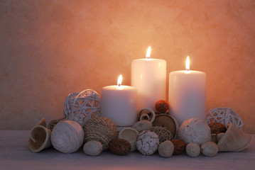 spa concept of white burning candles decorated in natural dried potpourri in spa setting