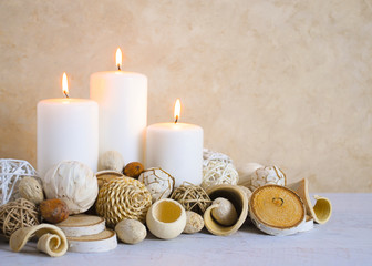 Fototapeta na wymiar spa concept of white burning candles decorated in natural dried potpourri in spa setting