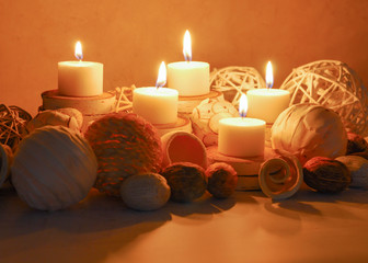 spa concept of white burning candles decorated in natural dried potpourri in spa setting