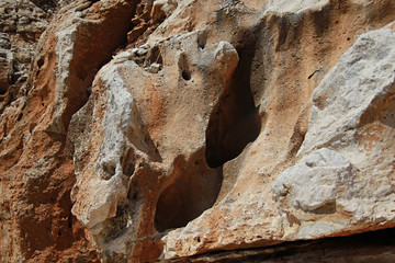 Ochreous porous rock on the beach of Albania, caves and mountains of the resort area