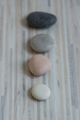 Row of gray zen stones on wooden mat, five pebbles in a row, massage pebbles, low depth of field