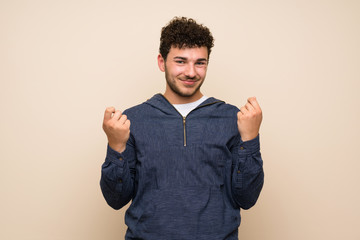 Man with curly hair over isolated wall making money gesture