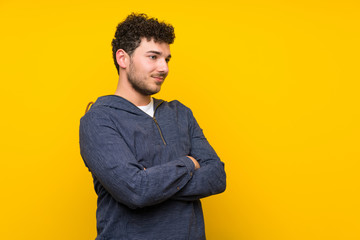 Young man over isolated yellow wall standing and looking to the side