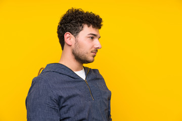 Fototapeta premium Young man over isolated yellow wall standing and looking side