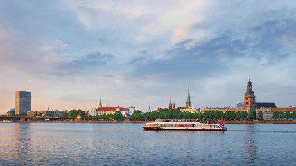 ship sails at sunset past the historical center of Riga
