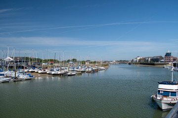 Fototapeta na wymiar River Arun Littlehampton looking north at low tide towards the recently opened Harbour Lights Cafe, yachts are moored on the west bank at the Yacht Club on a beautiful sunny July day in England.