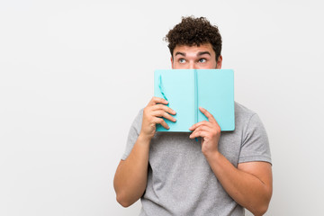 Man with curly hair over isolated wall holding and reading a book
