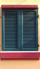 window with green shutters on orange wall