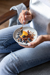 plate with granola and fresh berries in the hands of a young girl