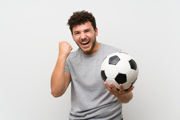 Man with curly hair over isolated wall holding a soccer ball