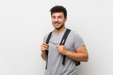 Man with curly hair over isolated wall with backpack