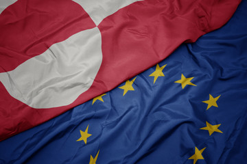 waving colorful flag of european union and flag of greenland.