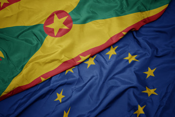 waving colorful flag of european union and flag of grenada.