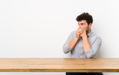 Young man with a table covering mouth and looking to the side