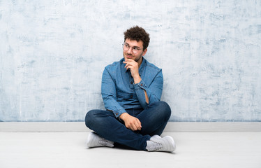 Young man sitting on the floor with glasses