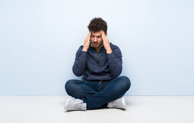Young man sitting on the floor with headache