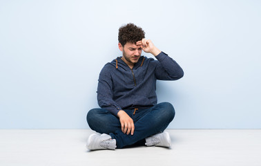 Young man sitting on the floor with tired and sick expression