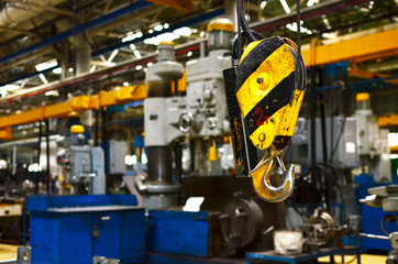 Fototapeta na wymiar Bridge lifting Crane Hook against the background of the Assembly Line industrial factory. The concept of a heavy automotive manufacturing process at an industrial plant, background, texture - Image