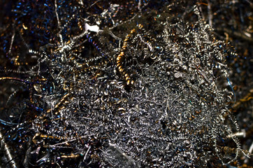 Steel scrap materials recycling. Aluminum chip waste after machining metal parts on a cnc lathe. Closeup twisted spiral steel shavings. Small roughness sharpness, possible granularity, blurred focus
