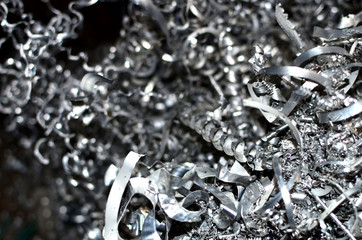 Steel scrap materials recycling. Aluminum chip waste after machining metal parts on a cnc lathe. Closeup twisted spiral steel shavings. Small roughness sharpness, possible granularity, blurred focus - obrazy, fototapety, plakaty