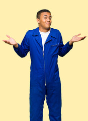Young afro american worker man making unimportant gesture while lifting the shoulders on isolated background