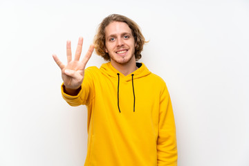 Blonde man with  sweatshirt over white wall happy and counting four with fingers