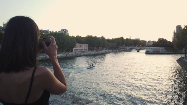 Young French woman takes photos of River Seine in Paris - evening view
