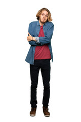 Fototapeta premium Full-length shot of Blonde man making doubts gesture while lifting the shoulders over isolated white background