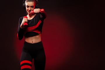Sporty fit woman, athlete with dumbbells makes fitness exercising on red background. Fitness and...