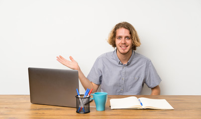 Blonde man with a laptop holding copyspace imaginary on the palm to insert an ad