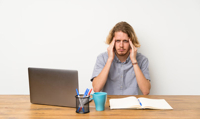 Blonde man with a laptop with headache