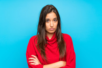 Obraz premium Young woman with red sweater over isolated blue background sad