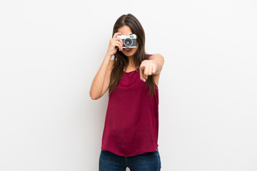 Young woman over isolated white background holding a camera