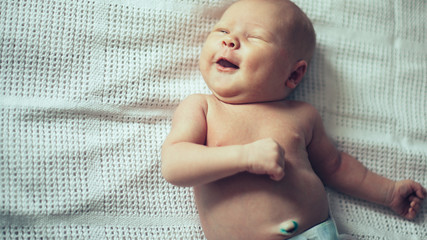 newborn smiling baby in a white diaper.
