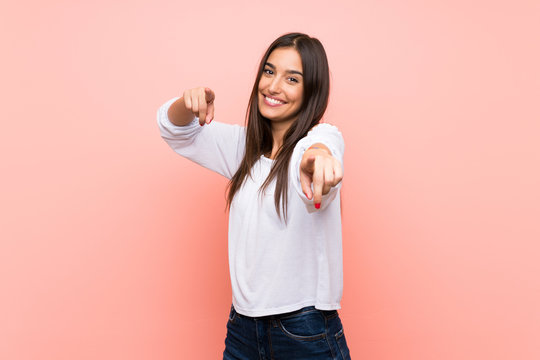 Young woman over isolated pink background points finger at you while smiling