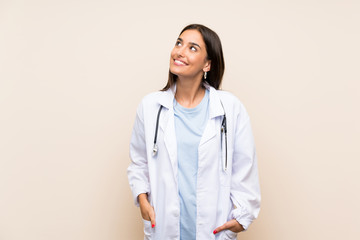 Young doctor woman over isolated background laughing and looking up