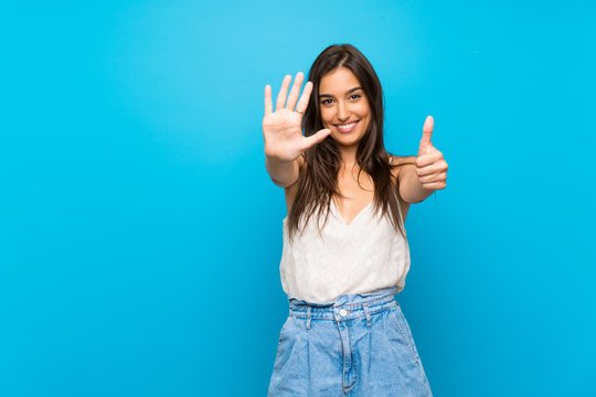 Young woman over isolated blue background counting six with fingers