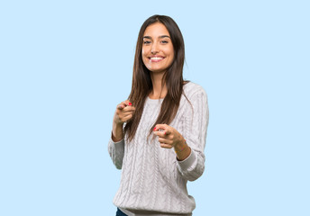 Young hispanic brunette woman pointing to the front and smiling over isolated background