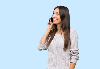 Young hispanic brunette woman keeping a conversation with the mobile phone over isolated background