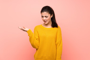 Teenager girl  over isolated pink wall making doubts gesture