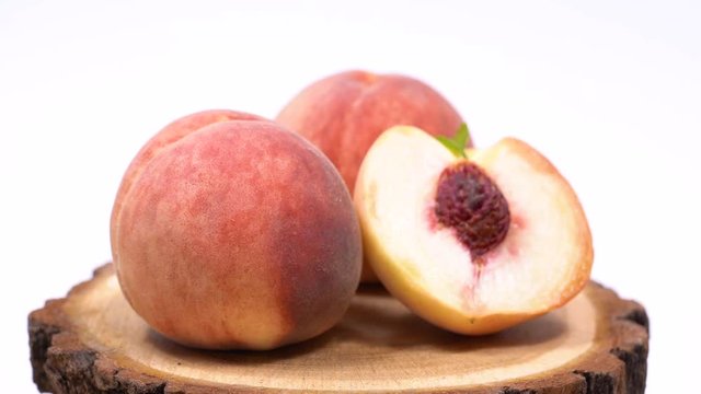Ripe white peaches rotate around its axis. Peaches on a white background. White peach on a wooden saw