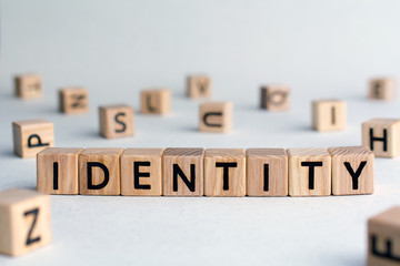 identity - word from wooden blocks with letters, individual different qualities of a person or group concept, random letters around, top view on wooden background